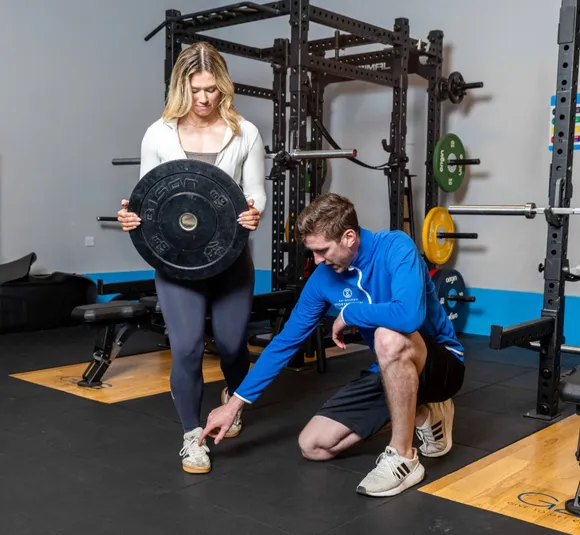 Peter O'Hanlon coaching a client through a squat in the gym